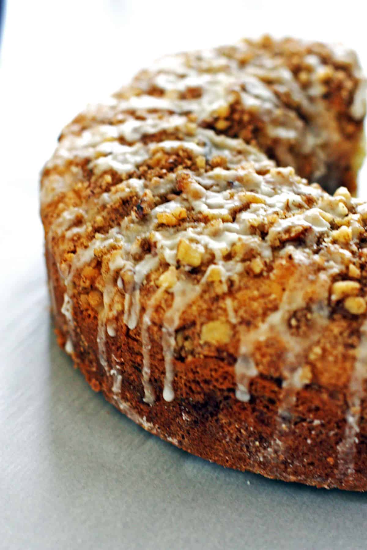 A cinnamon streusel coffee cake from the side with glaze dripping down.