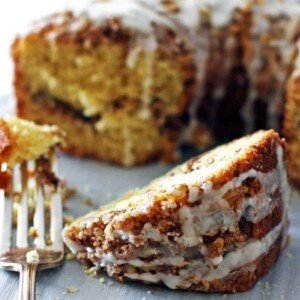 A slice of cinnamon streusel coffee cake in front of the rest of the cake.