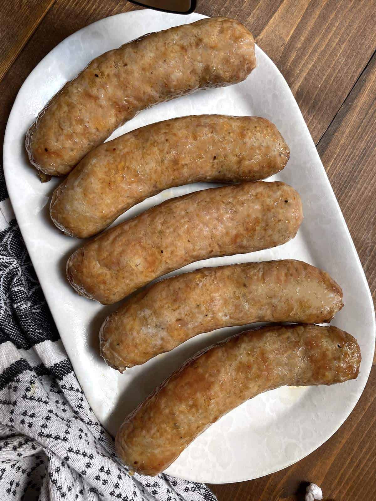 Whole cooked air fried Italian sausages on a white plate.