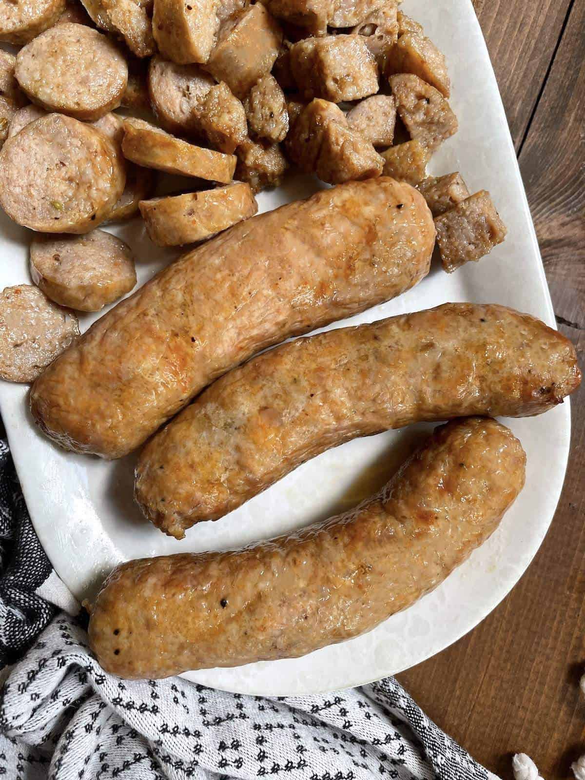 Air fried Italian sausages cut in different ways on a white plate.