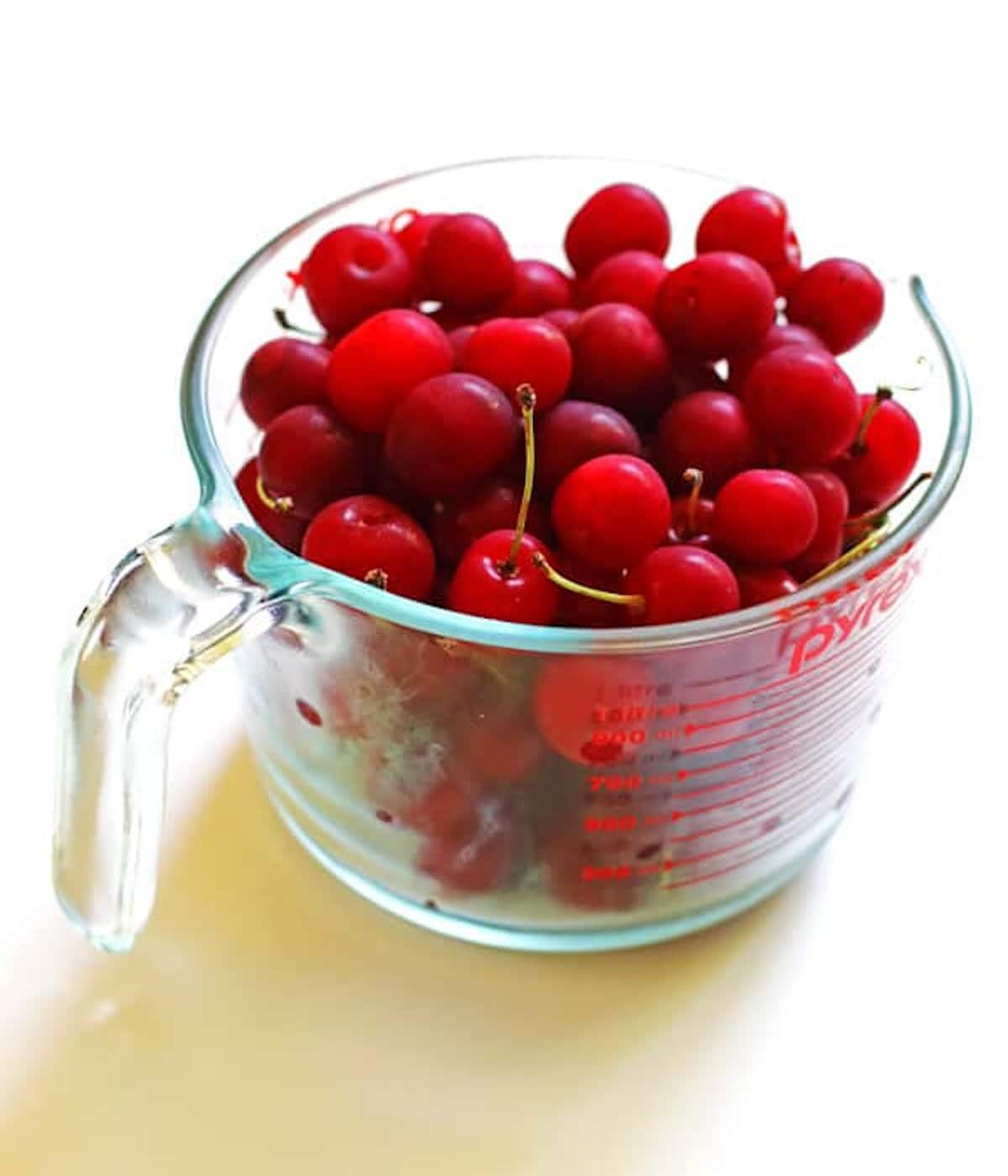 A pyrex cup of washed cherries.
