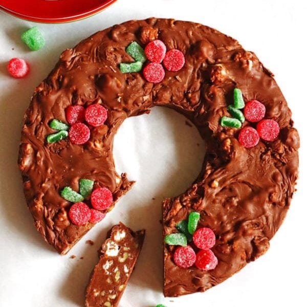 Homeamde chocolate fudge shaped as a Christmas wreath with gumdrops as berries on top of it.