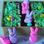 An Easter dirt cake for kids with coconut grass, m and ms, and peeps.