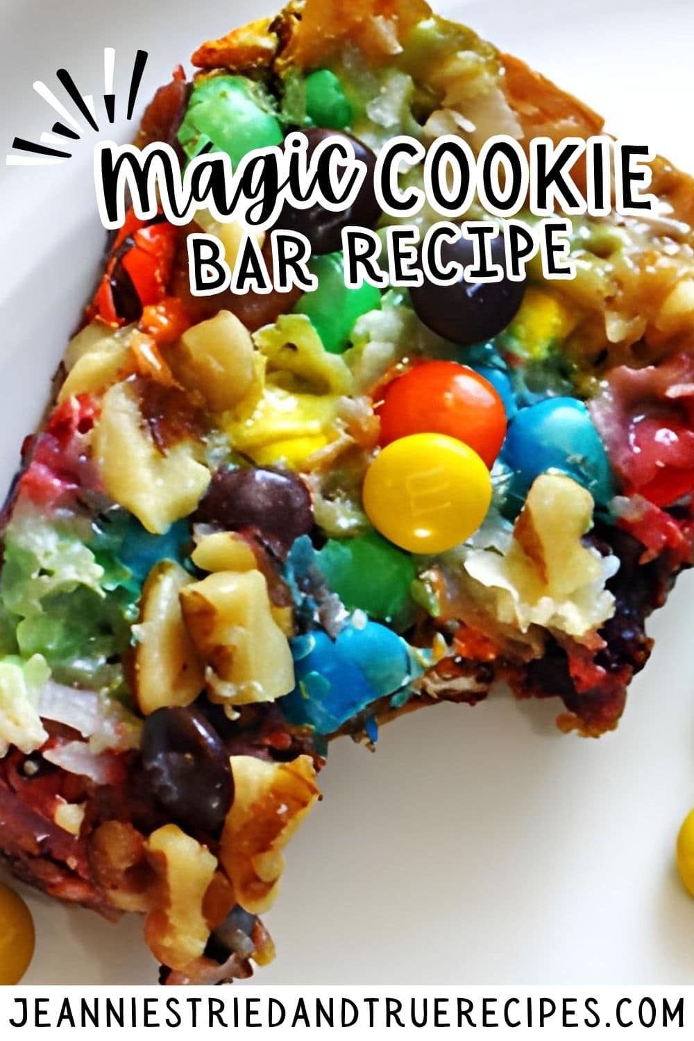 A pin image a magic cookie bar with nuts, coconut, chocolate chips, and mini m and ms on a white plate with a bite taken out of it.