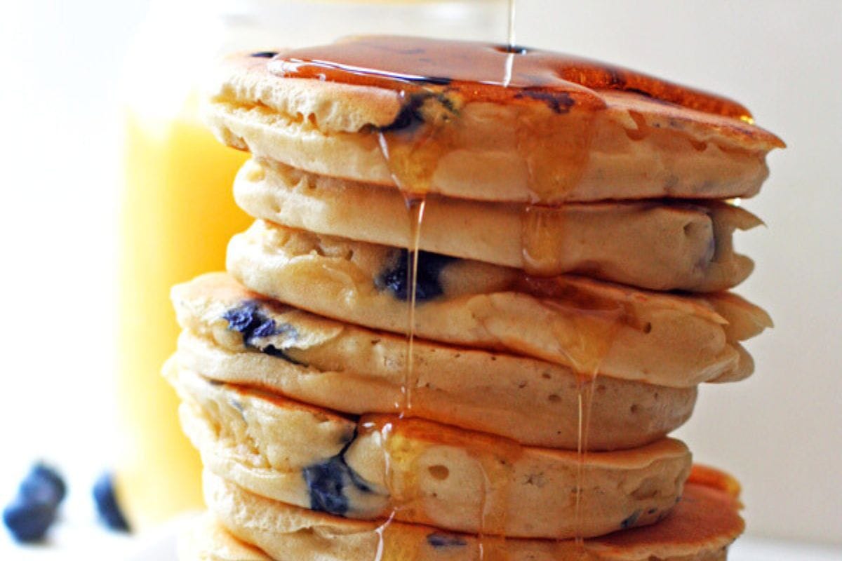 A stack of blueberry pancakes dripping in syrup.