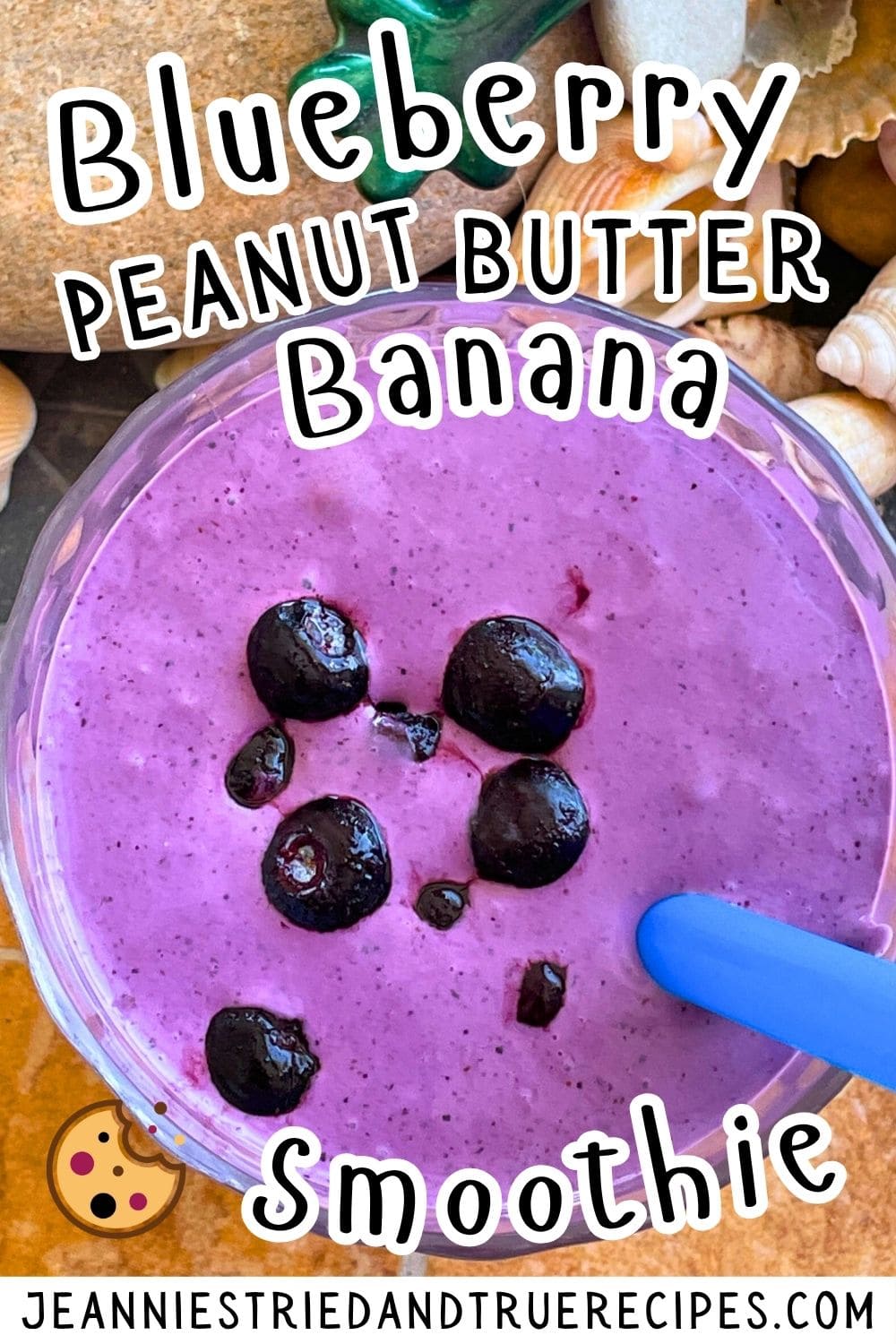 A pin image of a bluberry banana and peanut butter smoothie with blueberries on top on a tiled background with a blue straw and shells off to the side.